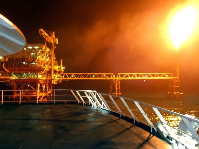 Plataforma petrolera offshore de noche con quemador encendido